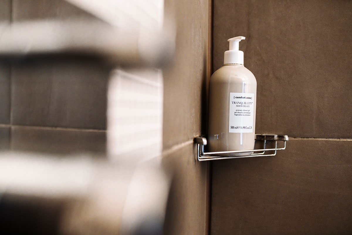 Close-up of a shower tray with a bottle of body wash in the single room of the Hotel Künstlerquartier Seezeichen.