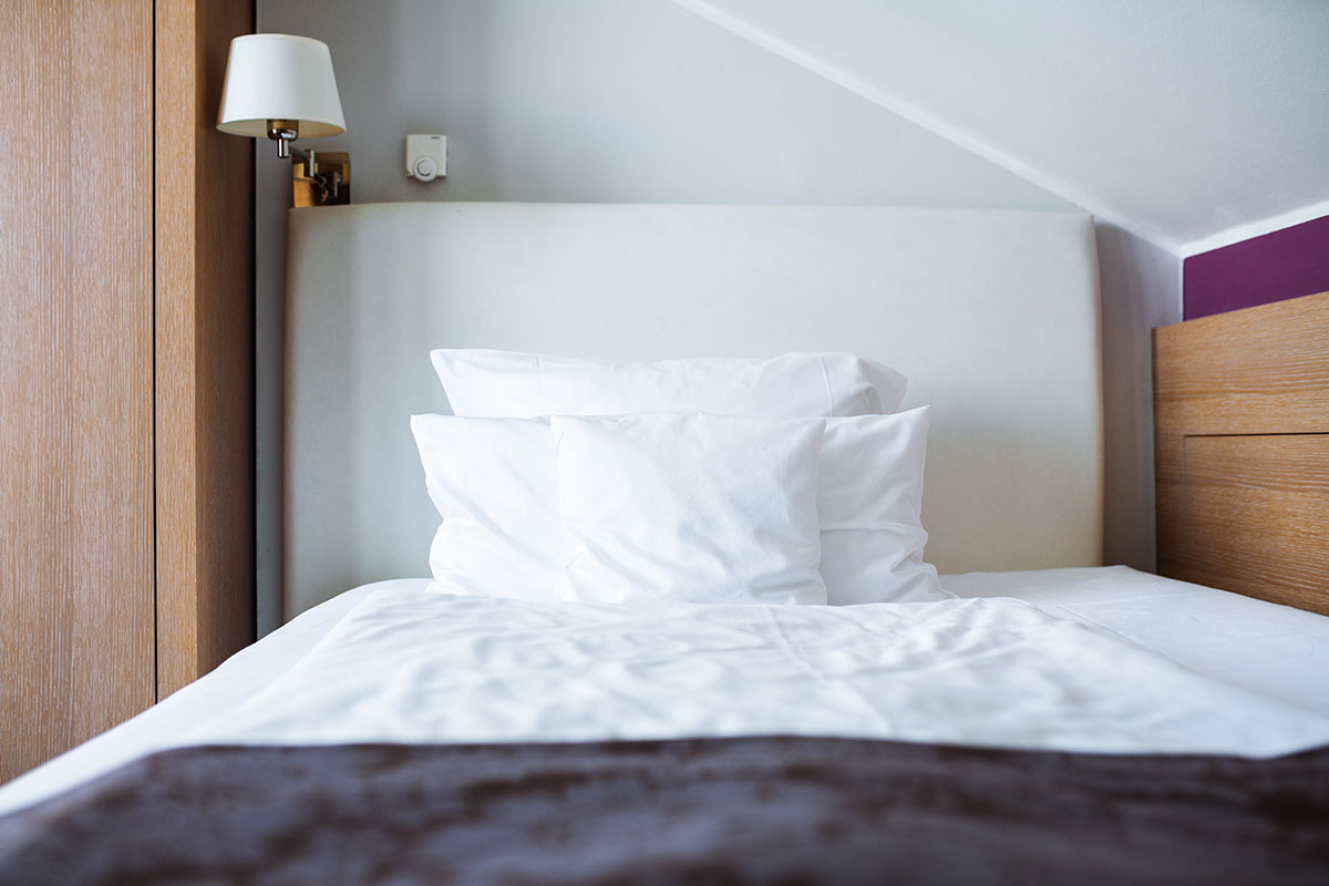 Inviting bed in the single room of the Hotel Künstlerquartier Seezeichen with soft pillows.