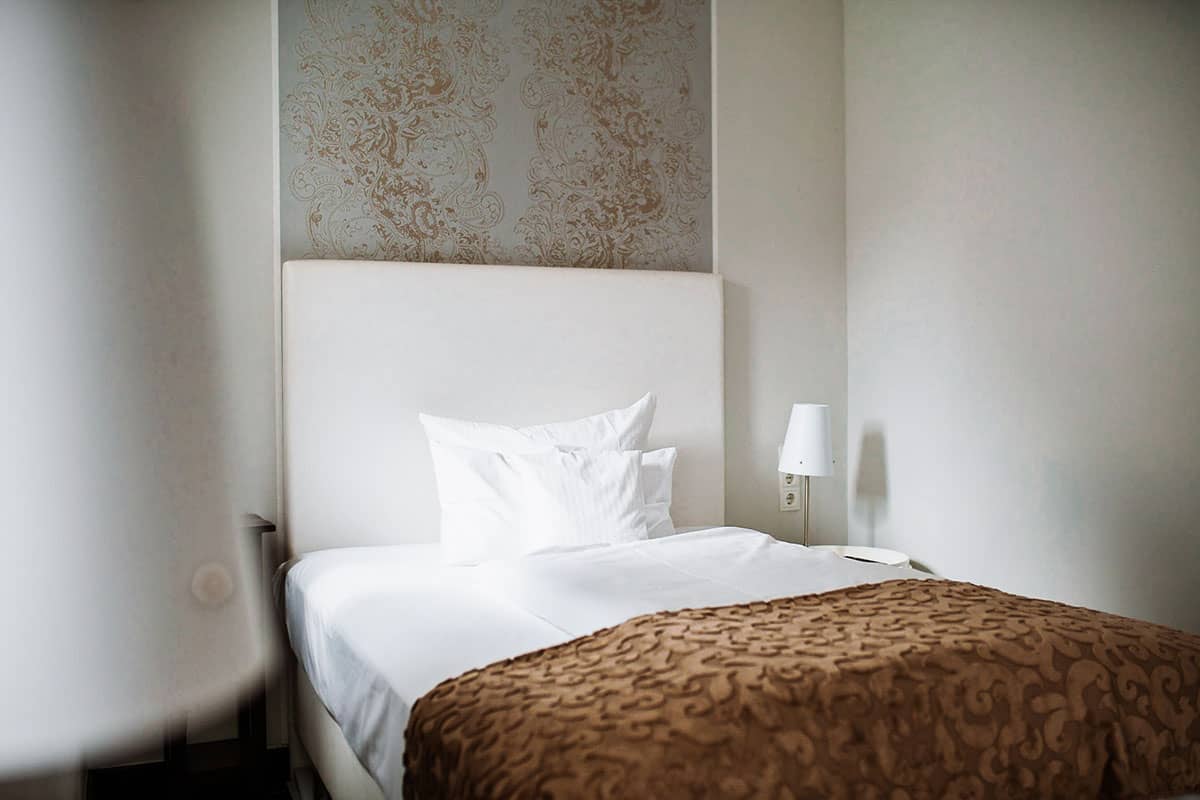Stylish single bed with elegant bed linen in the single room of the Hotel Künstlerquartier Seezeichen.