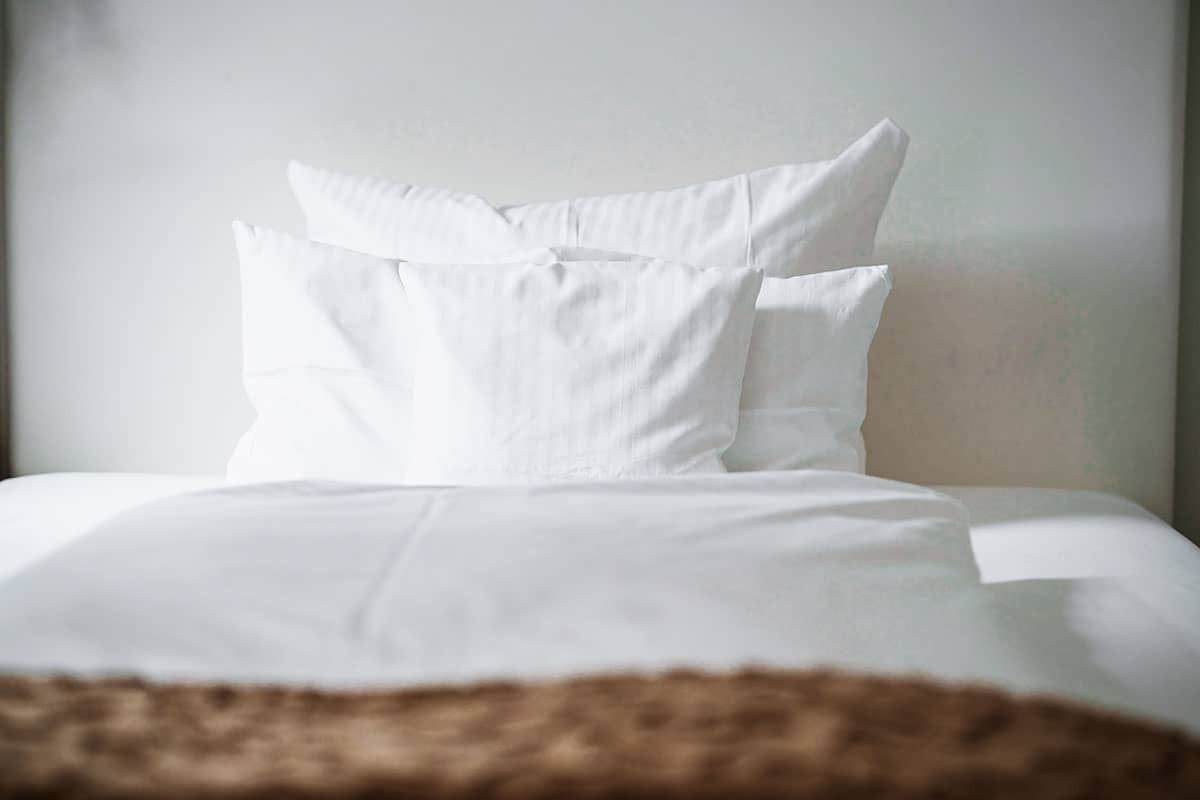 Modern single bed in the single room of the Hotel Künstlerquartier Seezeichen with decorative details.