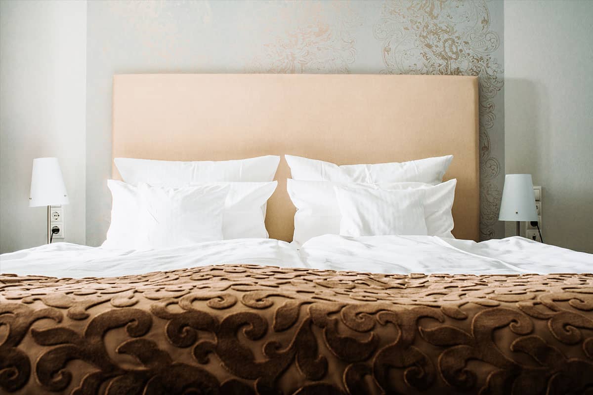 Gemütliches Doppelbett im First-Class-Doppelzimmer des Hotel Künstlerquartier Seezeichen mit eleganter Ausstattung.