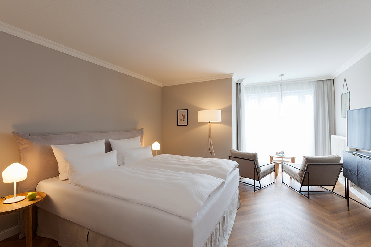Bright double room with large bed, cozy living area and modern furniture in the Vju Hotel with numerous offers.