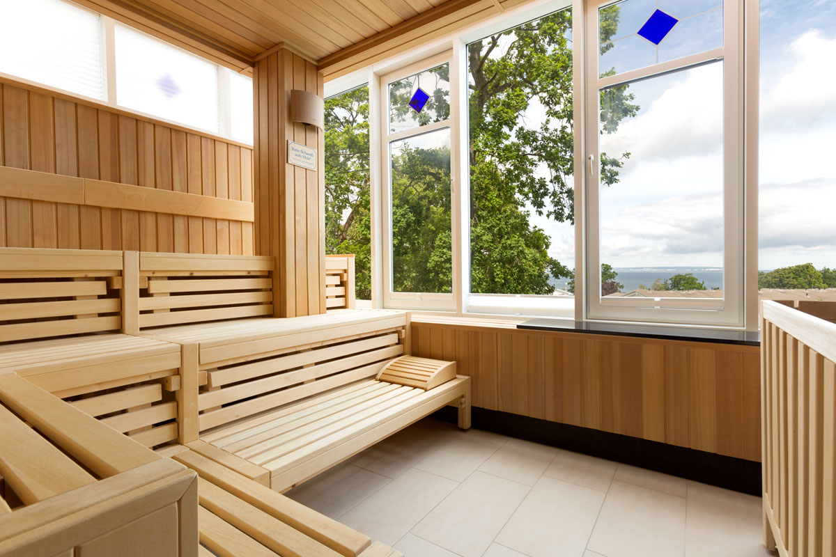 Interior of the sauna with wooden benches and panoramic windows with a view of the Baltic Sea in the Vju Hotel on Rügen with numerous offers.