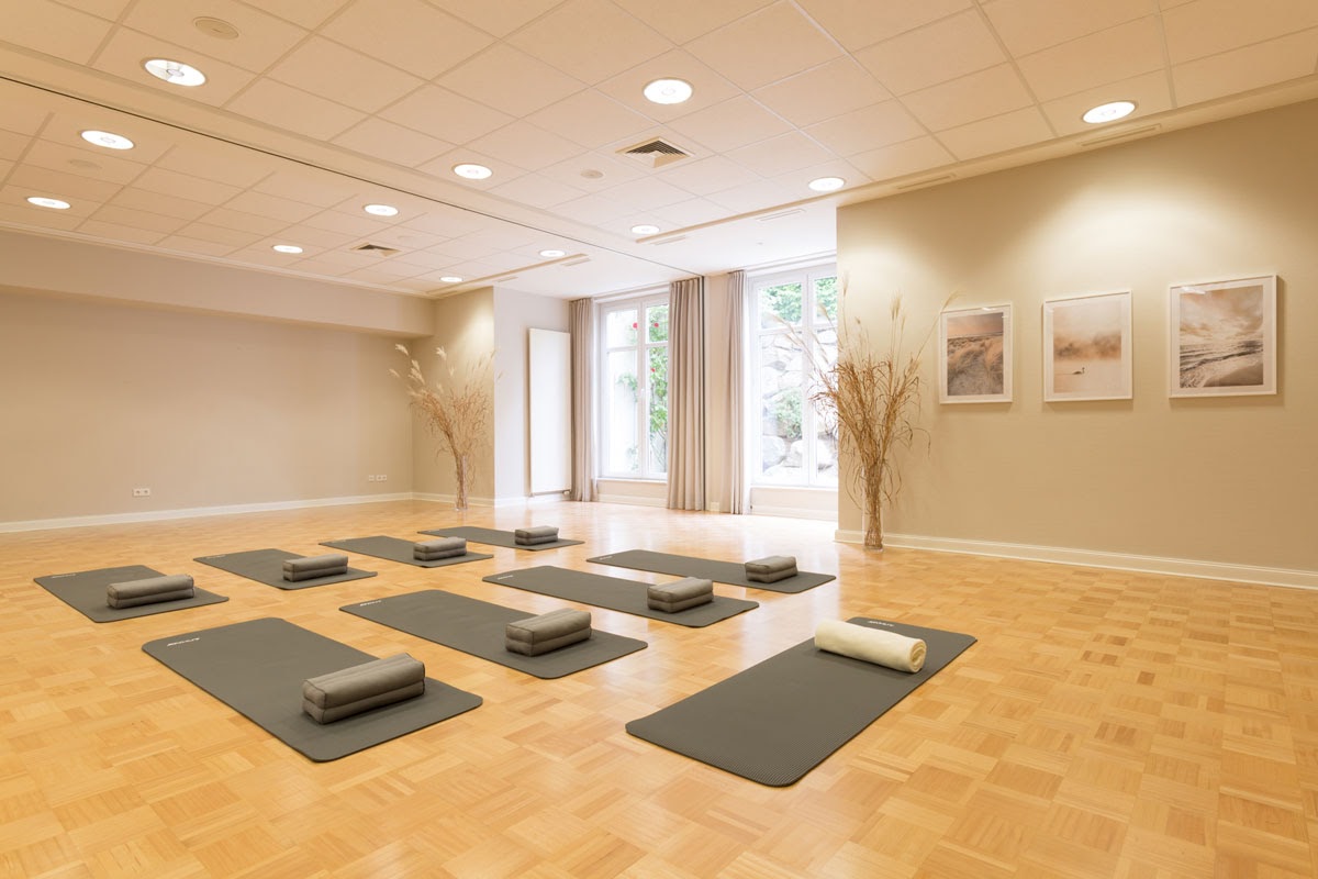 Bright yoga room at the Vju Hotel Rügen with mats, meditation cushions and soft towels for relaxing sessions.