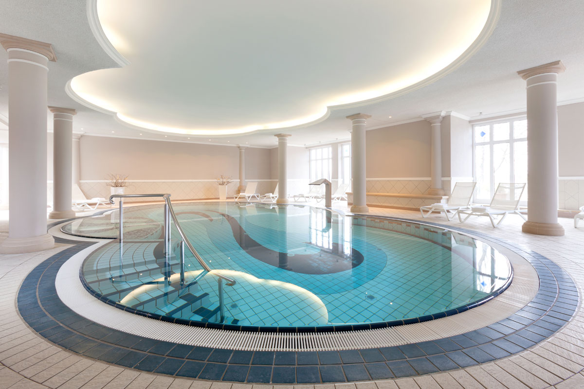 Indoor pool at the Vju Hotel with stylish lighting, comfortable loungers and a relaxed atmosphere during your vacation on Rügen.