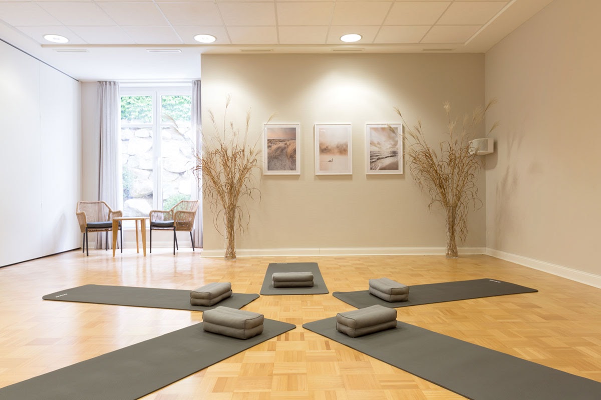 Harmonisch eingerichteter Yogaraum mit Matten, Kissen und natürlichem Licht für entspannte Übungen im Vju Hotel.