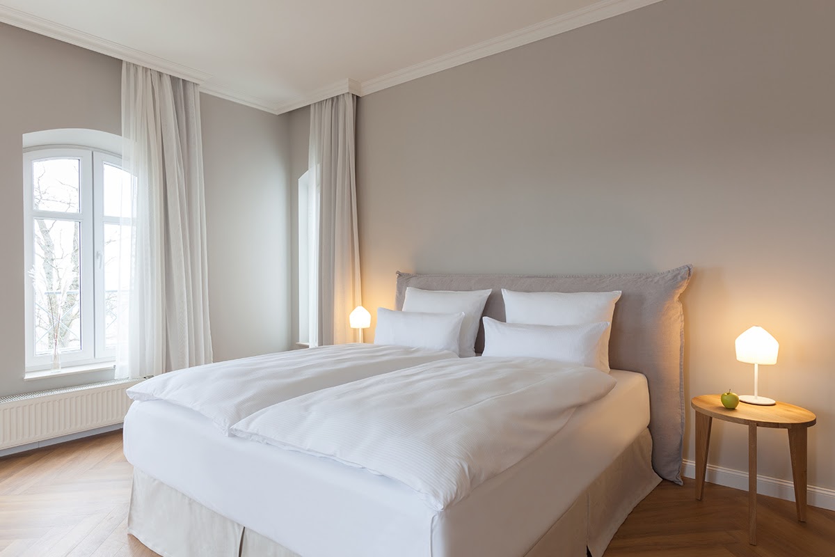 Helles Schlafzimmer mit großem Doppelbett und weicher Bettwäsche in der 2-Raum-Familiensuite im Vju Hotel auf Rügen.