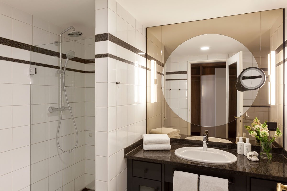 Helles Badezimmer im Queensize-Einzelzimmer des Vju Hotels mit großer Spiegelwand, Dusche und stilvollen Details.