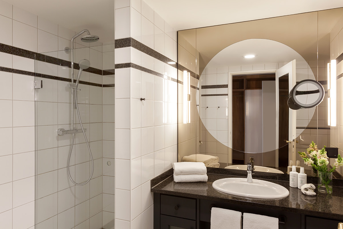 Modernes Badezimmer mit großer Dusche, edlen Details und Spiegelwand im Studio mit Ostseeblick des Vju Hotels.