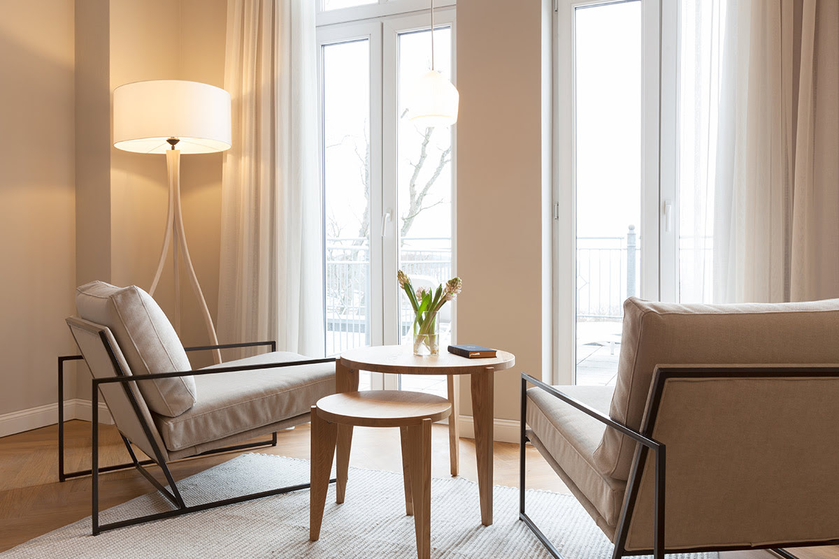 Heller Sitzbereich mit zwei Sesseln und bodentiefen Fenstern im Studio mit Ostseeblick des Vju Hotels.