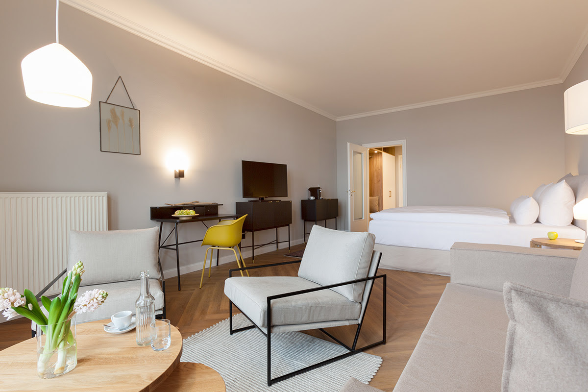 Wohnbereich des Studios mit Ostseeblick im Vju Hotel mit Sofa, Sesseln und Schreibtisch in modernem Design.