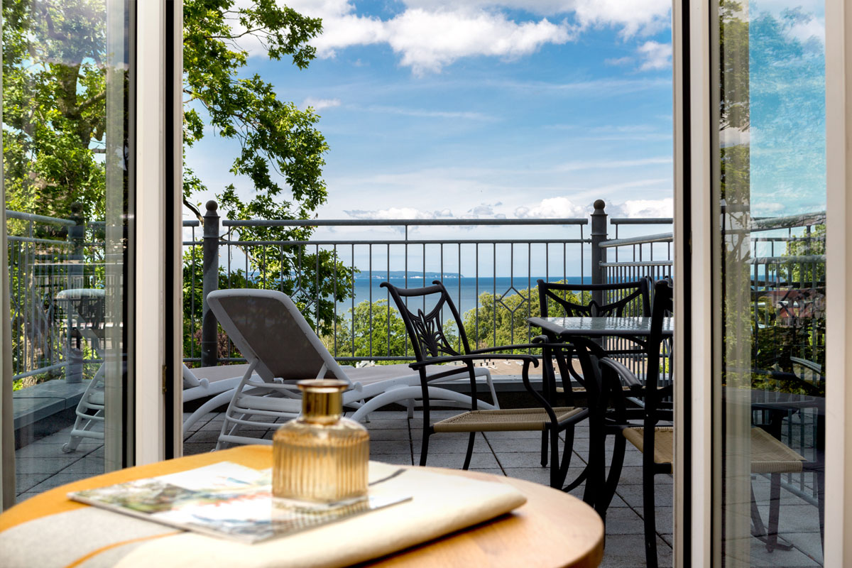 Private Terrasse des Studios mit Ostseeblick im Vju Hotel mit Sitzgruppe, Liegestühlen und Panoramablick über die Küste.