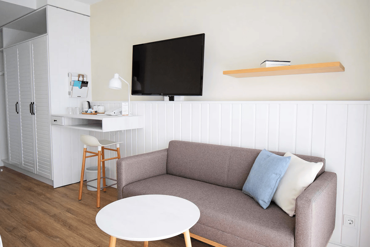 Cozy seating area in the Buhne room of the Wyn. Strandhotel with cushions, flatscreen TV and minimalist furnishings.