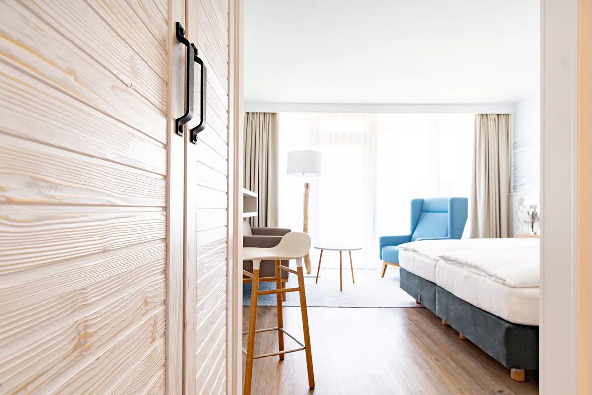 Entrance area of the Buhne room in the Wyn. Strandhotel with natural wood wardrobe and warm light.