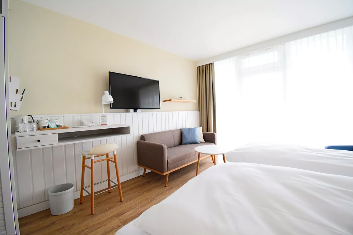 Stylishly furnished room Buhne in the Wyn. Strandhotel with desk, seating area and floor-to-ceiling windows.