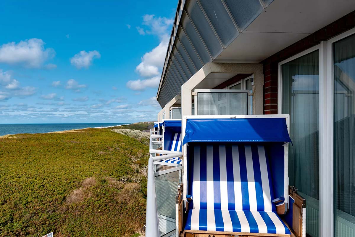 Private balcony in the Meerzeit room at the Wyn. Strandhotel with a beach chair and breathtaking views of the Sylt coastline.