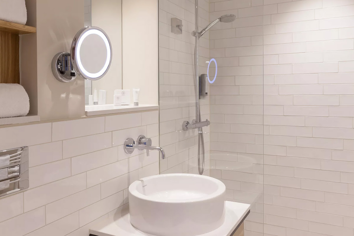 Bright hotel bathroom of the Meerzeit room in the Wyn. Strandhotel with a spacious glass shower, modern washbasin and stylish tiles.