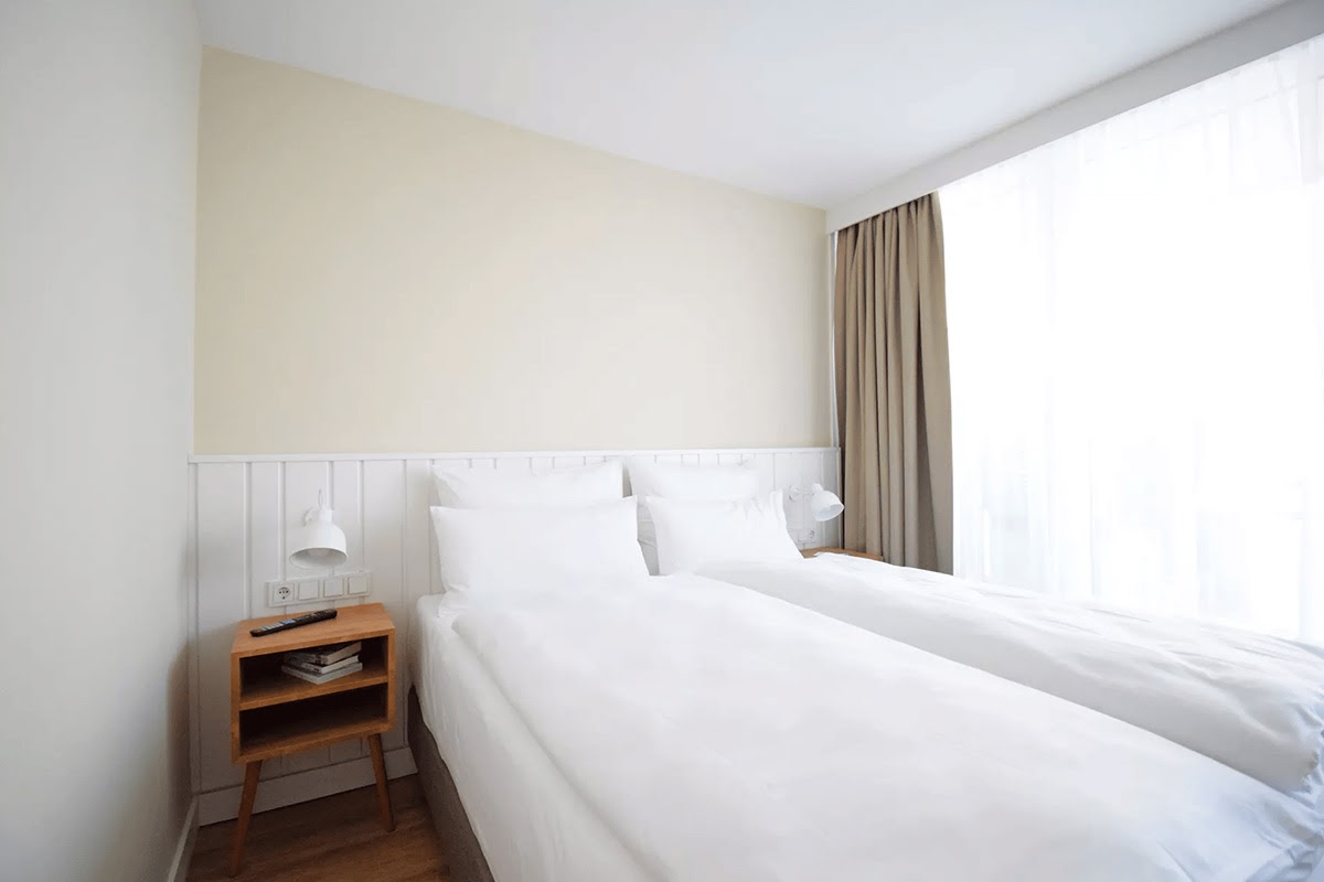 Cozy bedroom with double bed and daylight in the Westerland room of the Wyn. Strandhotel on Sylt.