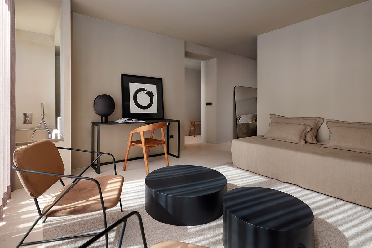 Modern eingerichtetes Hotelzimmer mit beigen Möbeln, zwei schwarzen Tischen und großem Kunstwerk auf Mallorca.
