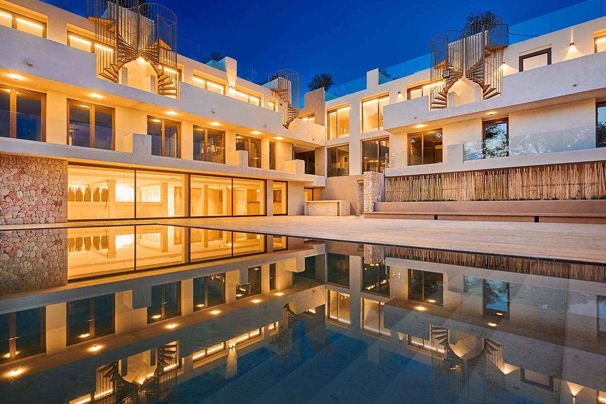 Moderne Poollandschaft mit reflektierendem Pool und stimmungsvoller Beleuchtung bei Nacht im Barefoot Hotel Mallorca.