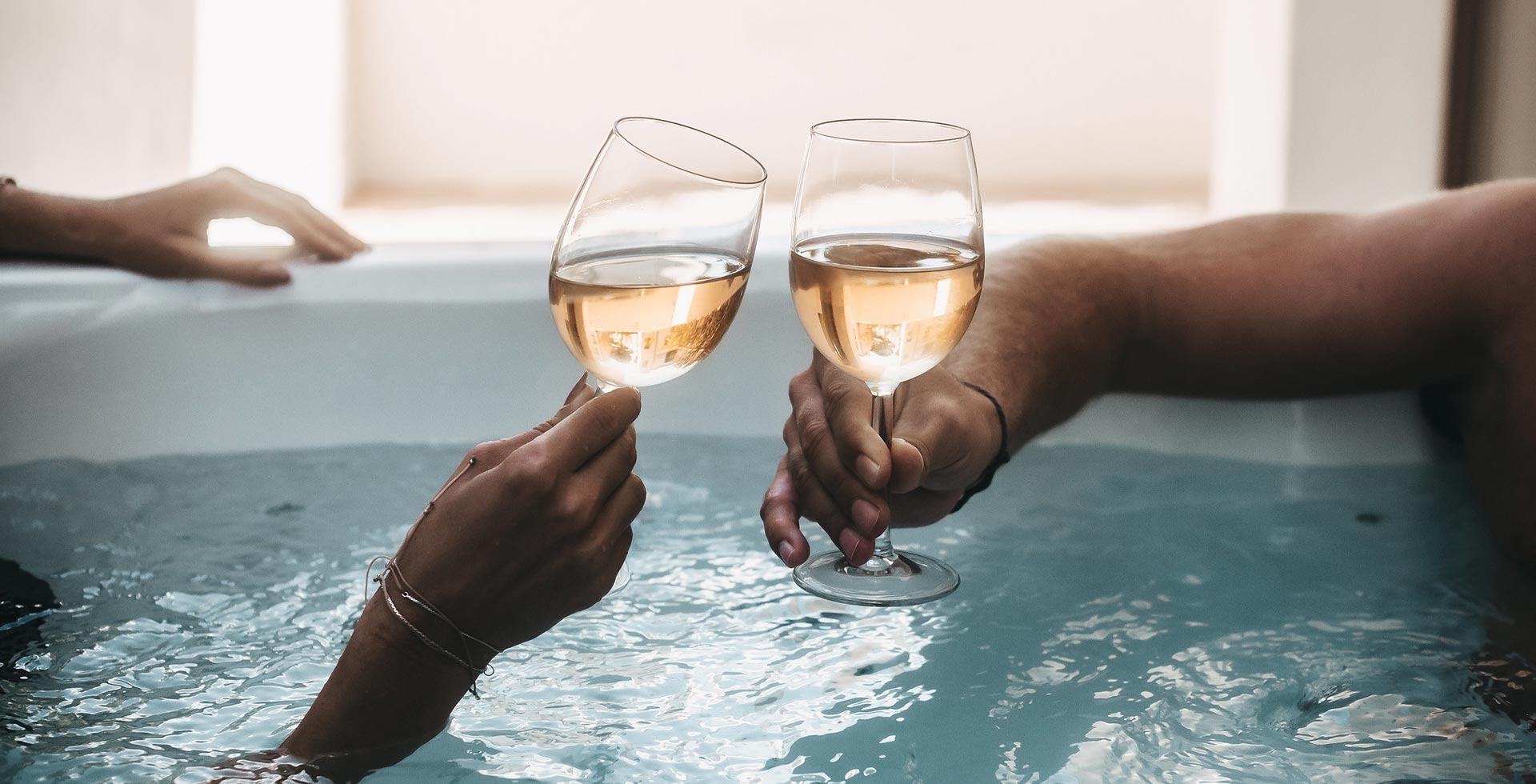 Two people toast with wine in the whirlpool.