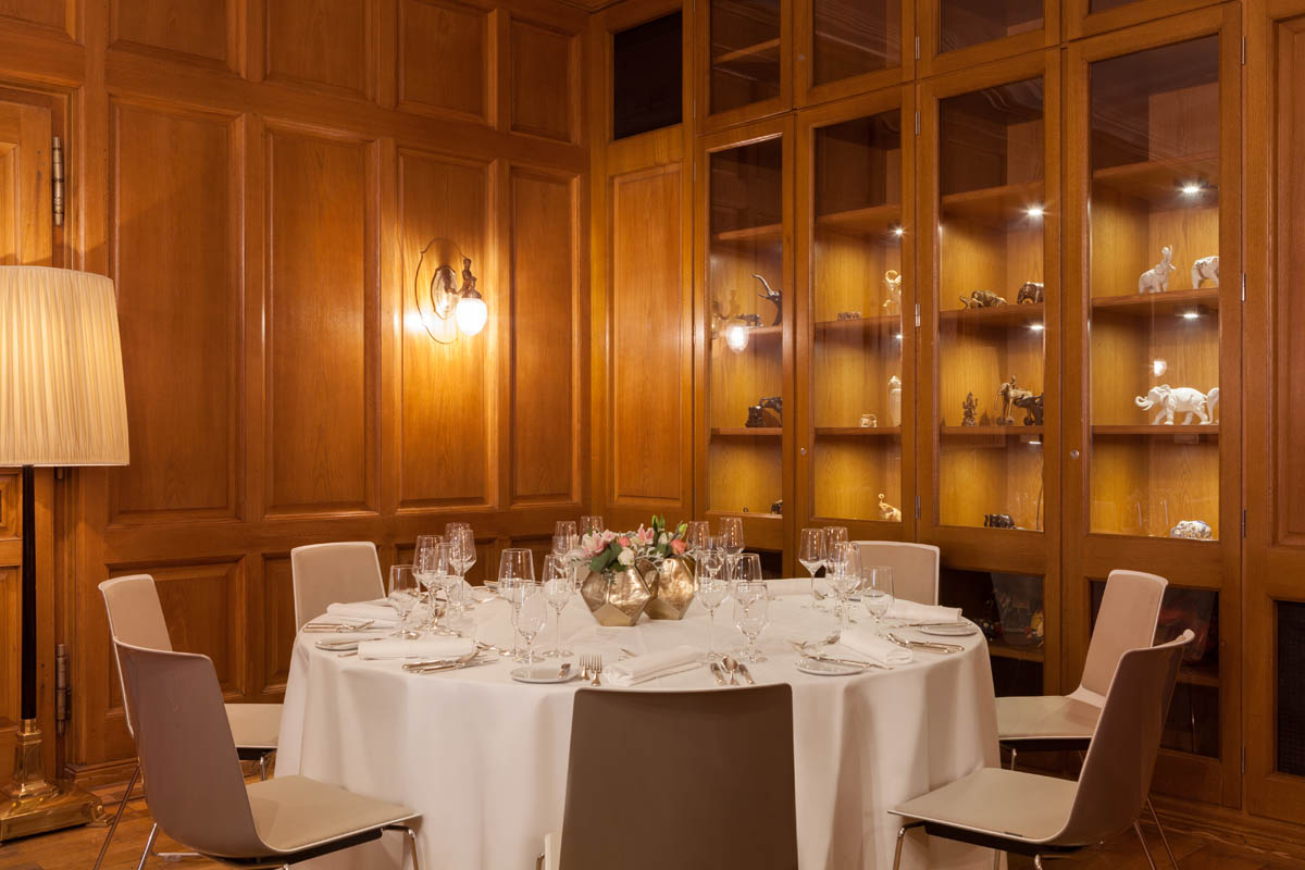 Set table in the private dining room of the Hotel Elephant Weimar surrounded by wooden paneling and decorative display cases.