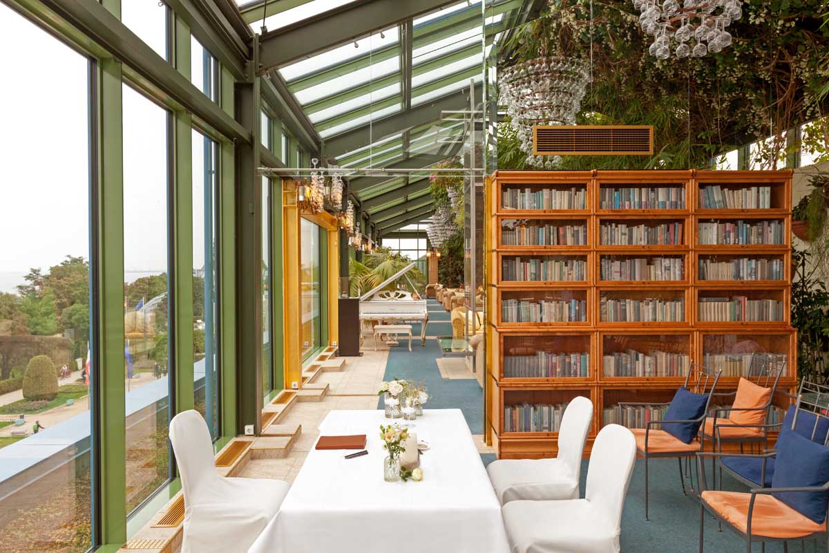 Salon Tucholsky in the Kaiserhof Heringsdorf on Usedom, equipped with bookcases, tables and panoramic windows facing the sea.