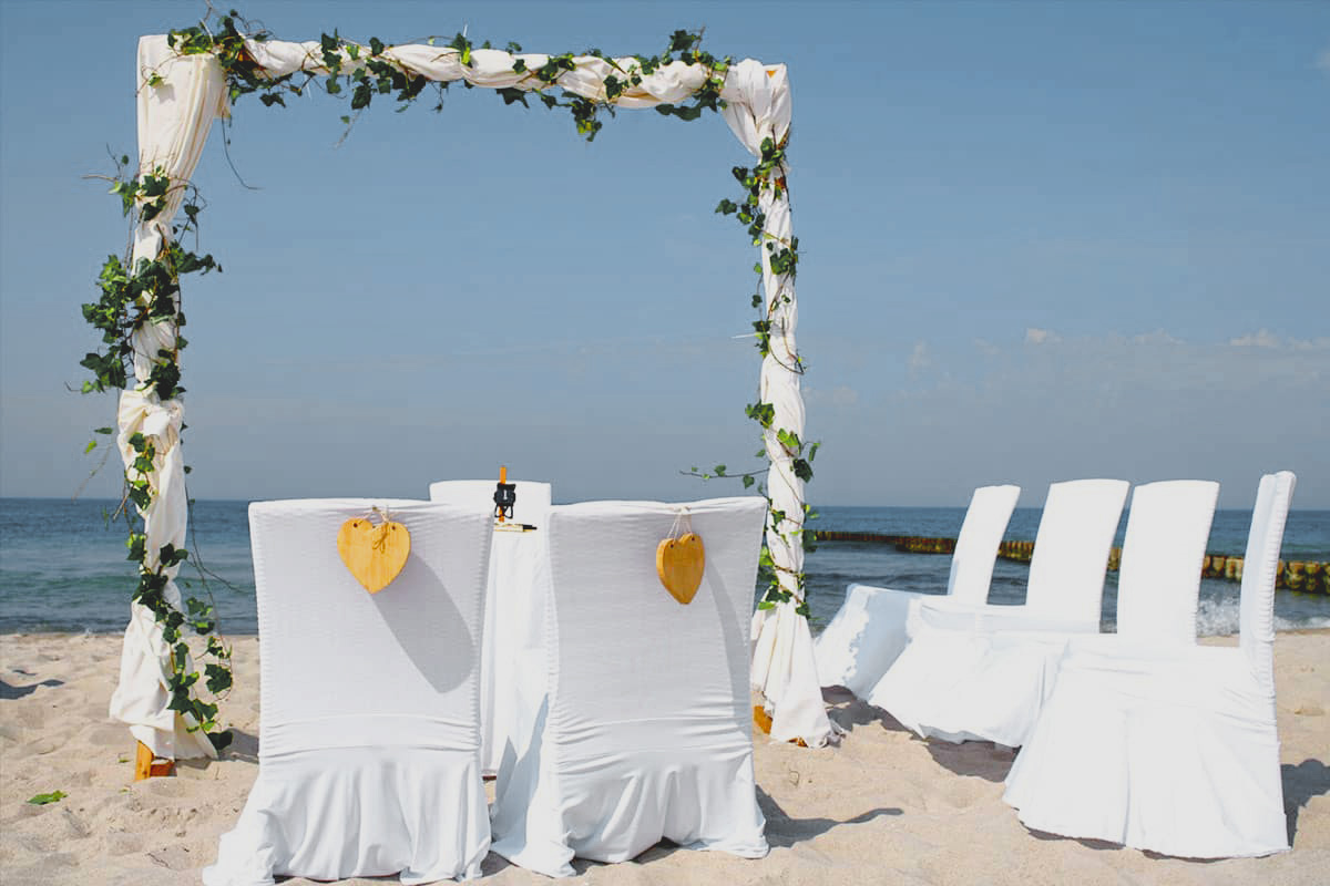 White chairs and wedding arch on the sandy beach with a view of the sea for a beach wedding.
