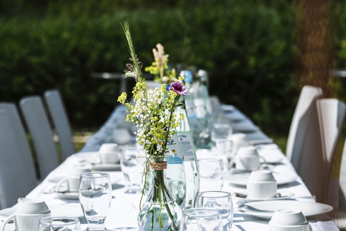 Long outdoor table with flower arrangement and dishes for a wedding in the Hotel Seezeichen.