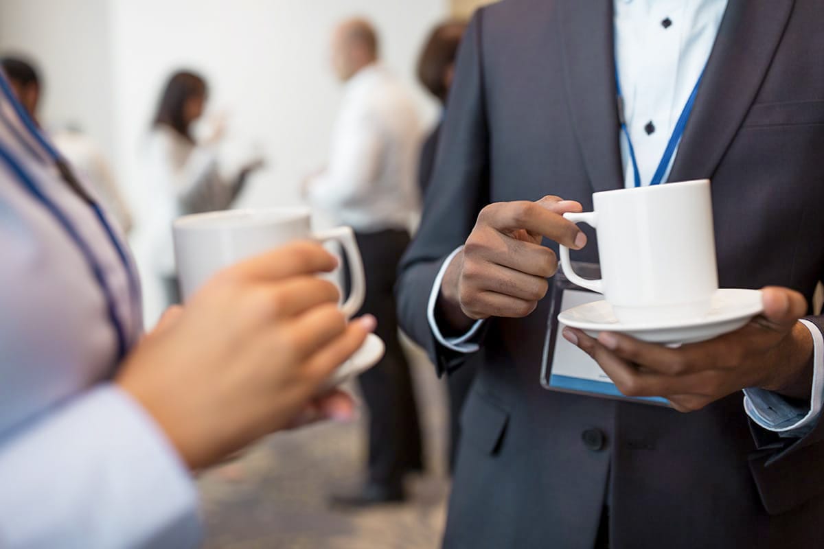 Close-up of people with coffee cups networking, conference offer in the artists' quarter sea sign for events.