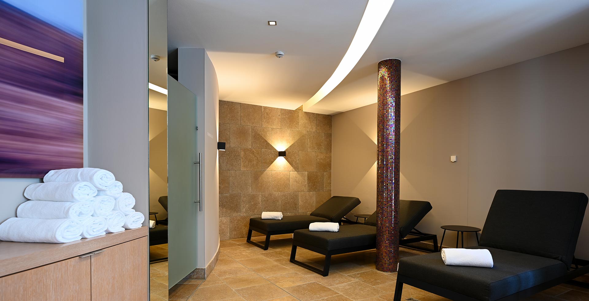 The modern relaxation area, featuring earthy tones and lavender accents, offers pure relaxation with its comfortable loungers.